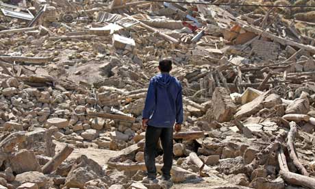 A man stands on the debris of destroyed buildings after an earthquake in north-west Iran