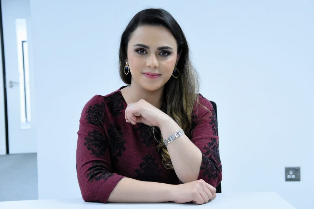 Samaneh sits in a TV studio, wears red blouse