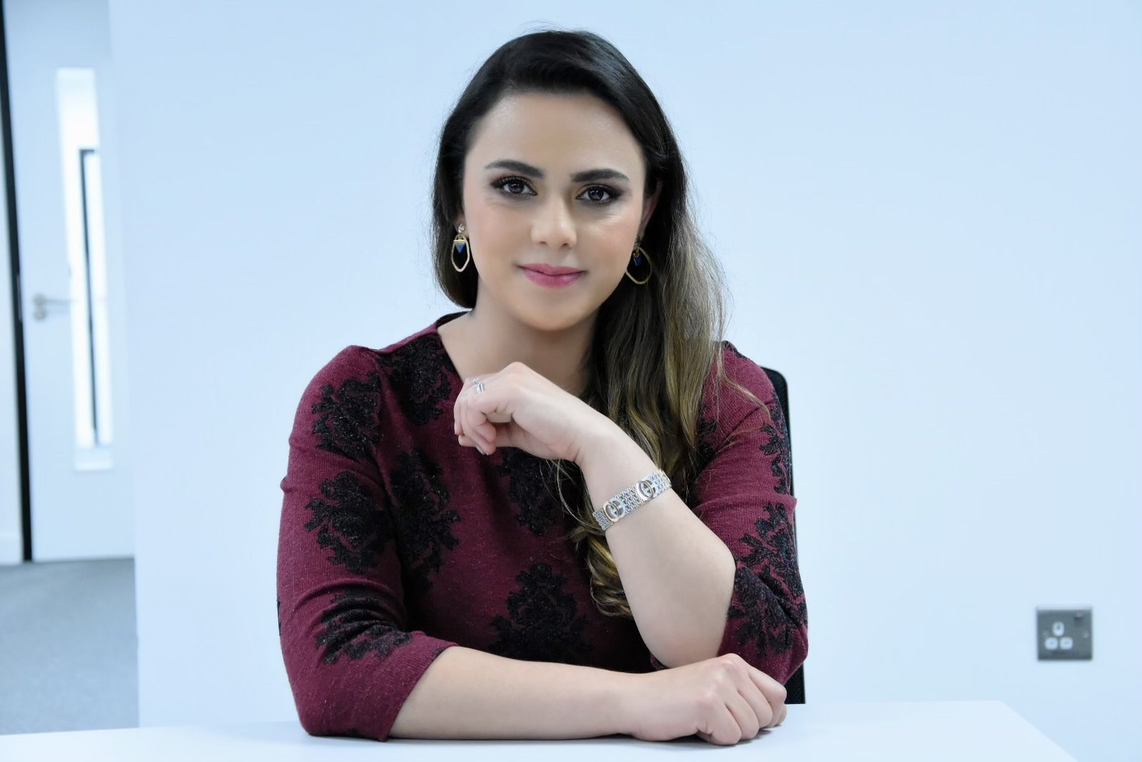 Samaneh sits in a TV studio, wears red blouse